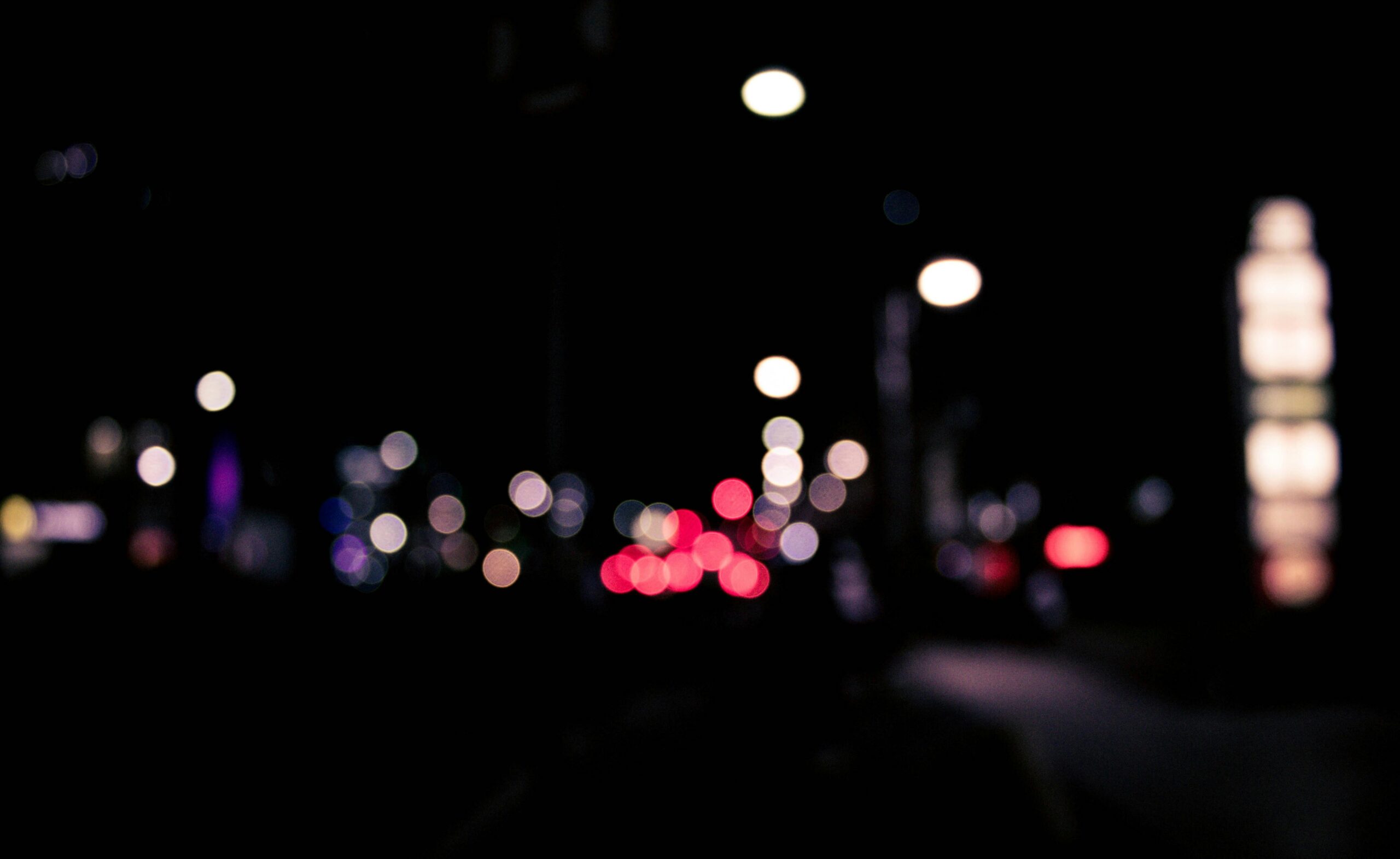 Blurred urban nighttime scene with colorful bokeh lights creating a dreamy effect.